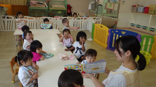 ７月りす１組お部屋で絵本の読み聞かせを見ているところ