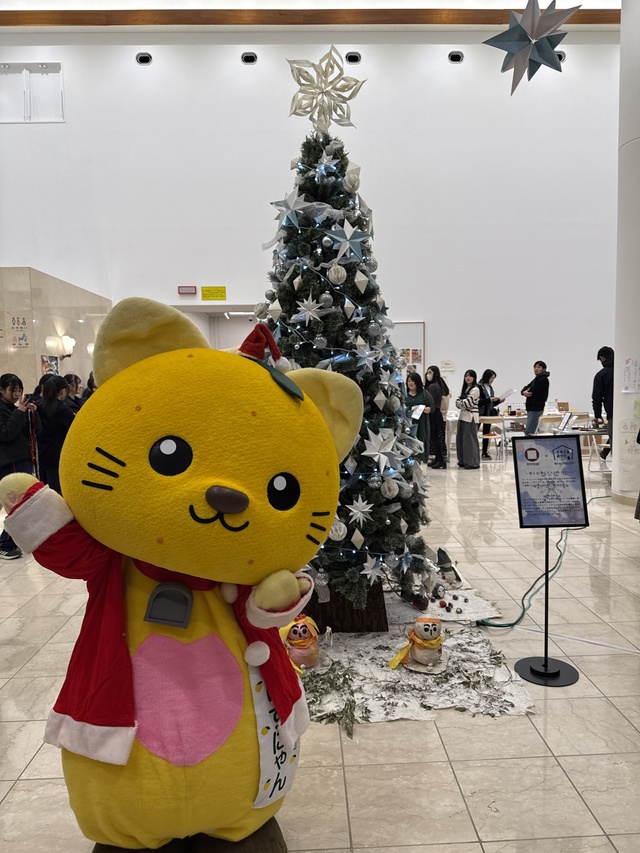 サンタクロースの衣装を着てツリーの前に立つゆずにゃん
