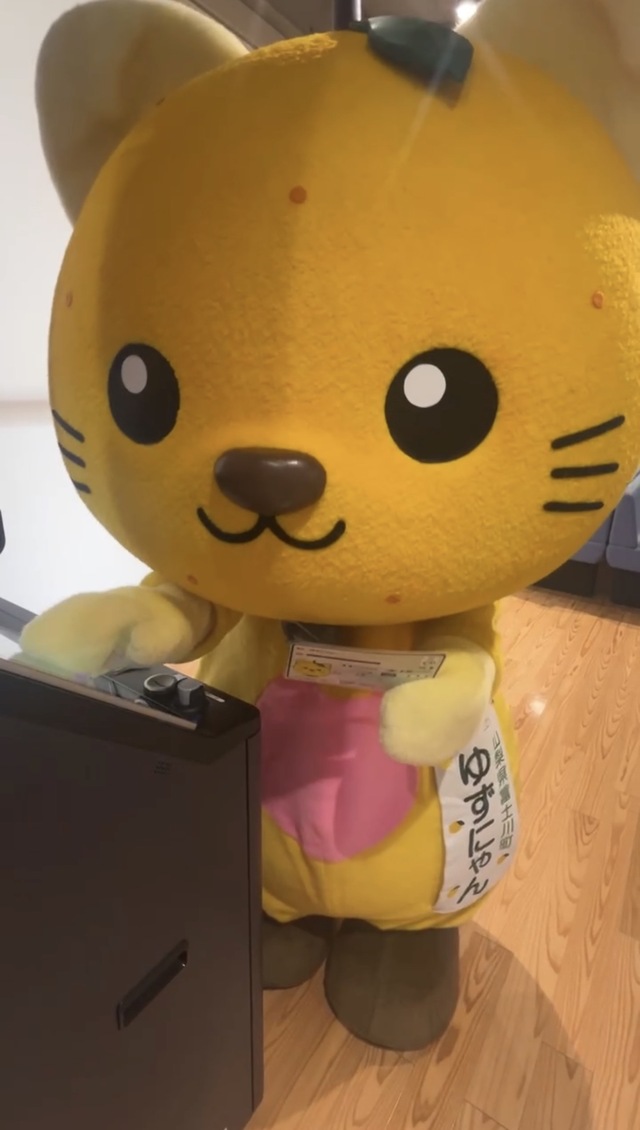 マイナンバーカードを持ちながら操作説明を受けるゆずにゃん